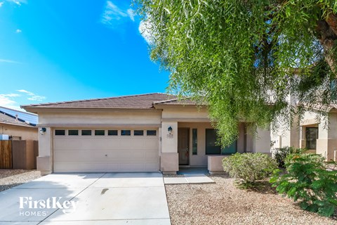 a white house with a garage door and a tree