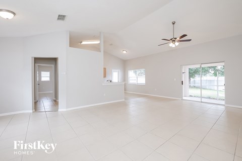 an empty living room with white tile floors and a ceiling fan