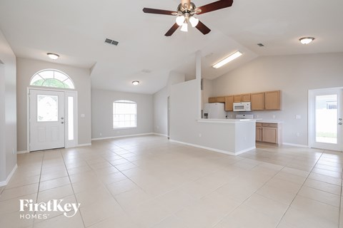 an empty living room and kitchen with a ceiling fan