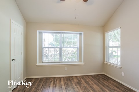 the living room of a home with a large window and wooden floors