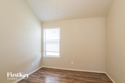 a bedroom with wood floors and white walls and a window