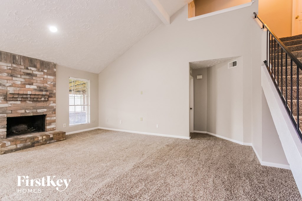 a spacious living room with a fireplace and carpeted floors