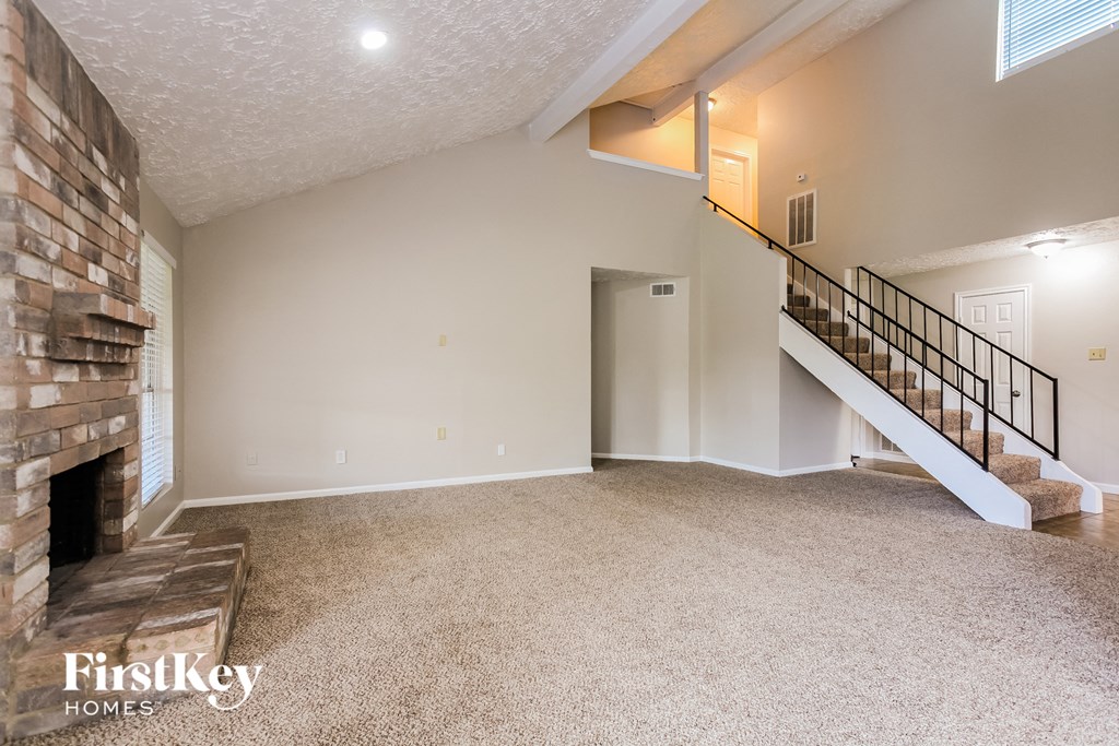 the living room of an empty house with a fireplace and a staircase
