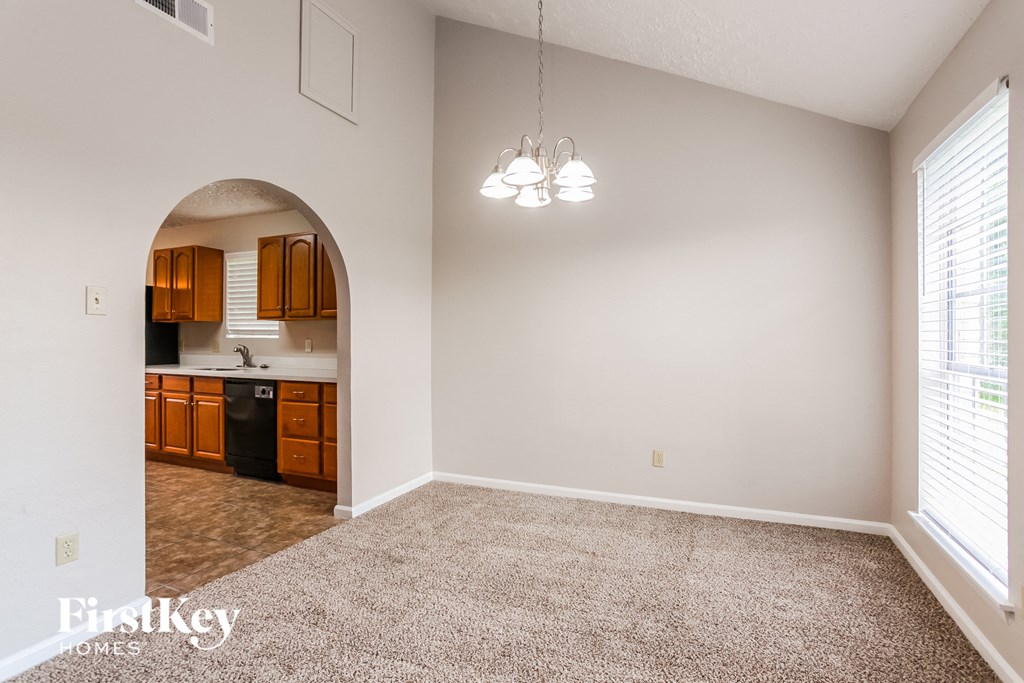 a living room with a carpeted floor and a kitchen
