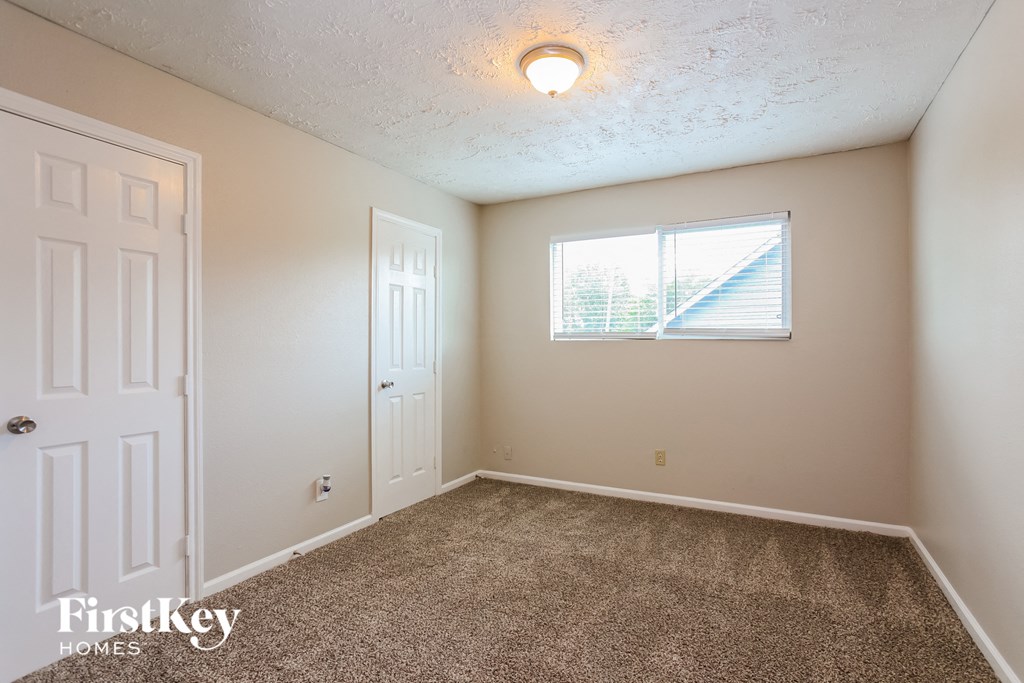an empty bedroom with carpet and a window
