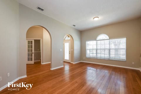 A spacious room with wooden floors and arched doorways.