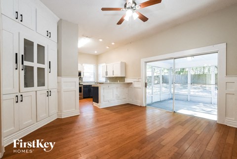 A spacious kitchen with wooden floors and a ceiling fan.