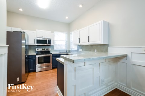 A kitchen with white cabinets and a wooden floor.