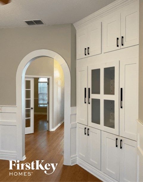 A kitchen with white cabinets and a wooden floor.