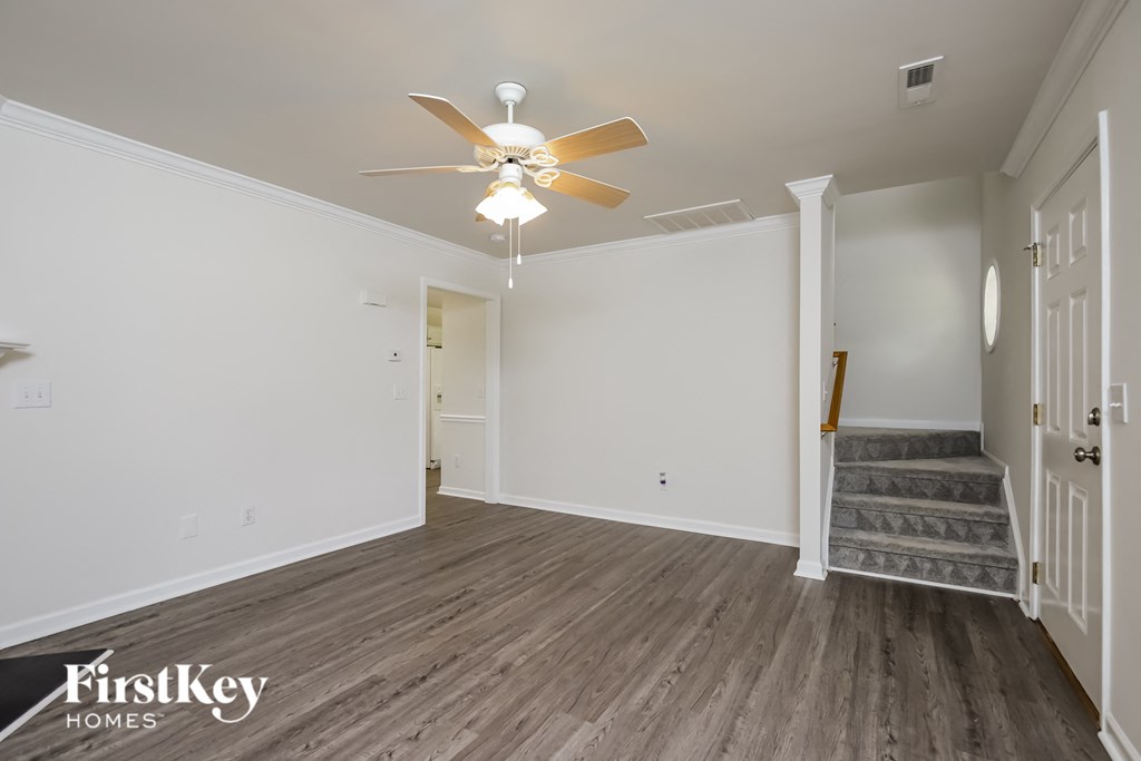 A spacious room with a staircase leading to the second floor.