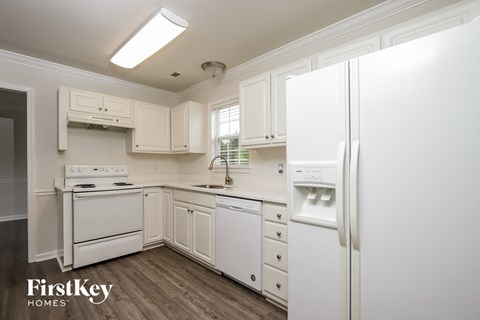 A kitchen with white appliances and cabinets.