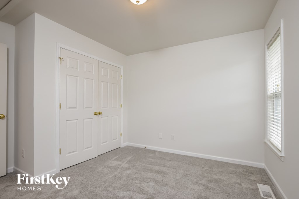 A bedroom with a white door and carpeted floor.