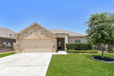a beige brick house with a garage door and a lawn