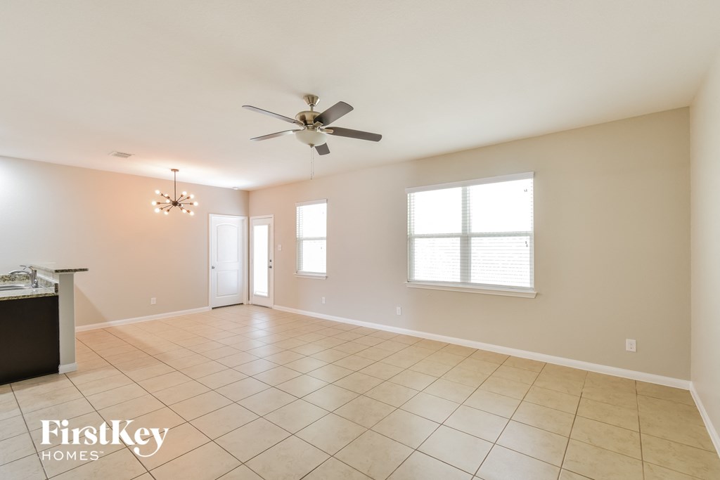 an empty living room with a ceiling fan and tiled floors