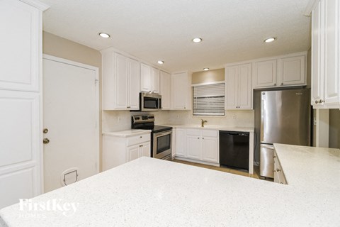 A kitchen with white cabinets and appliances.