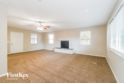 A spacious living room with a television and a ceiling fan.