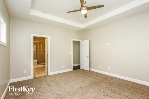 A spacious room with a ceiling fan and two doors.