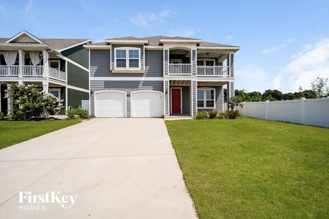 a blue house with a white fence and a driveway