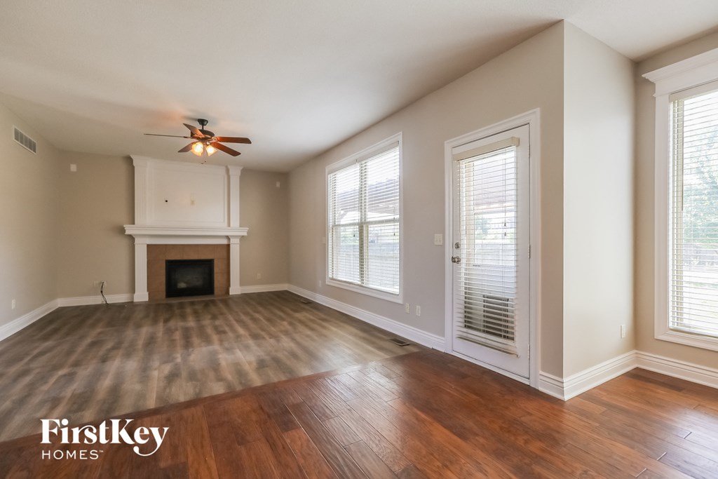an empty living room with a fireplace and a ceiling fan