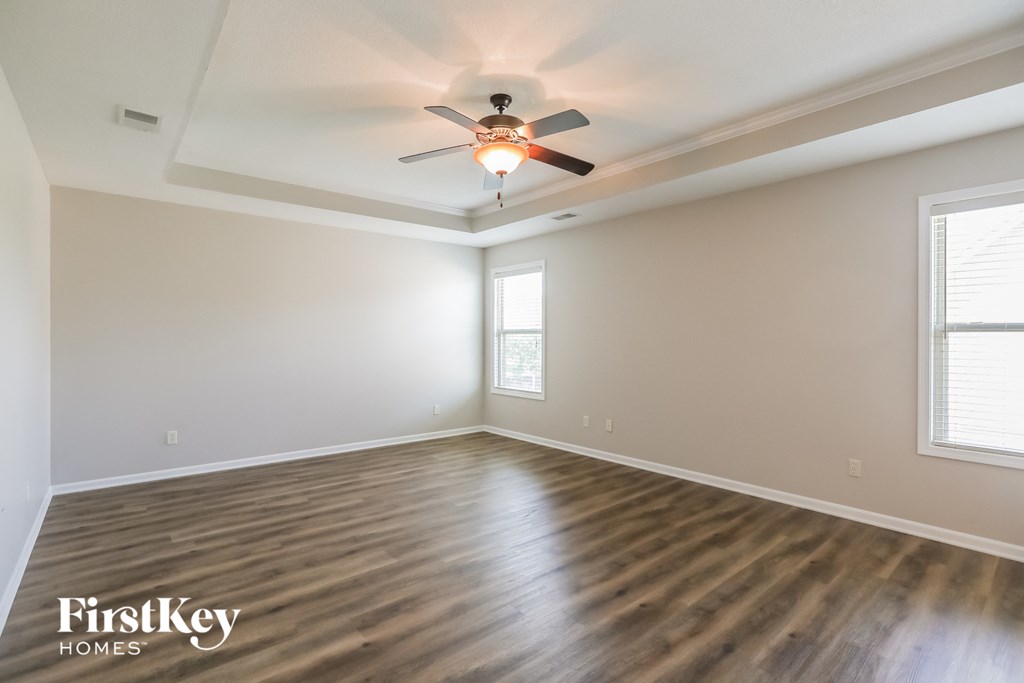 the spacious living room with hardwood flooring and a ceiling fan