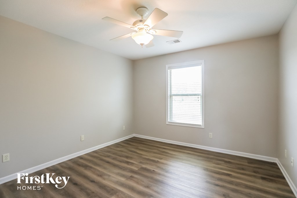 the spacious living room with wood floors and a ceiling fan