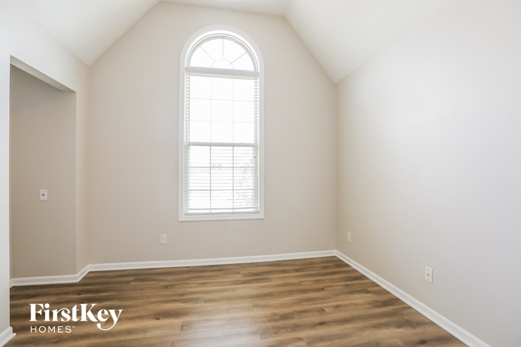 the second bedroom with hardwood flooring and a large window