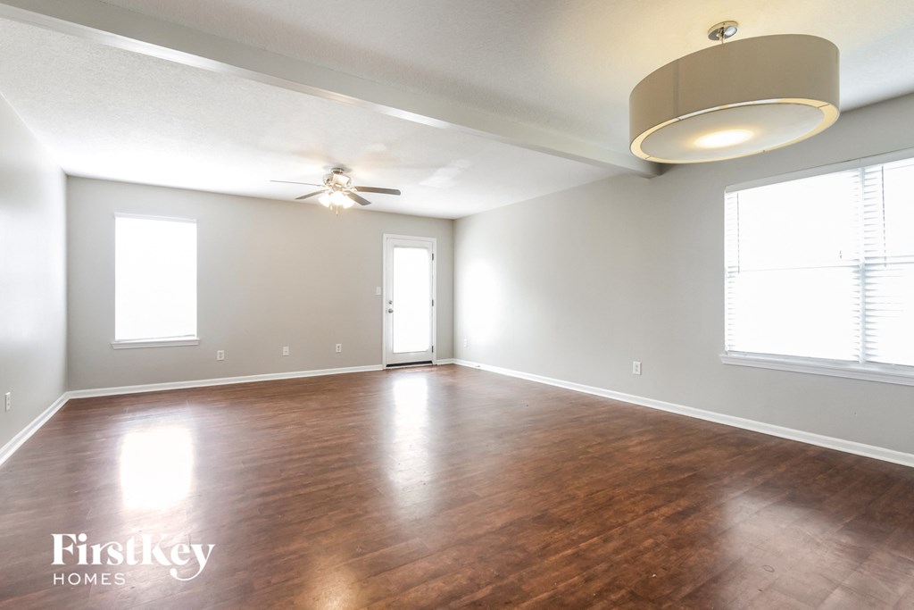 A spacious room with wooden floors and a ceiling fan.