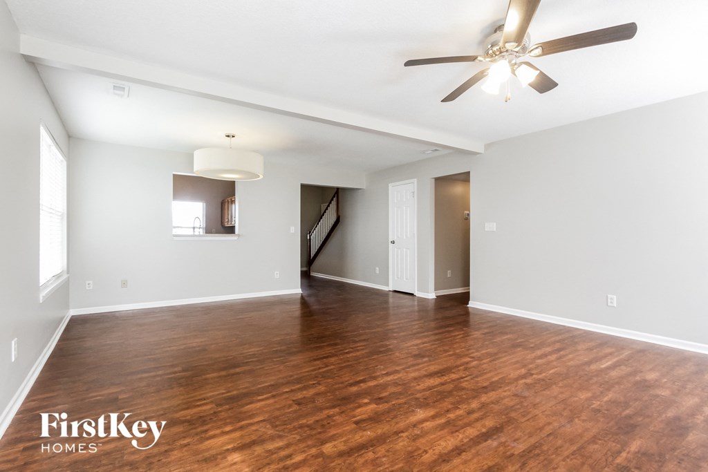 A spacious room with wooden floors and a ceiling fan.