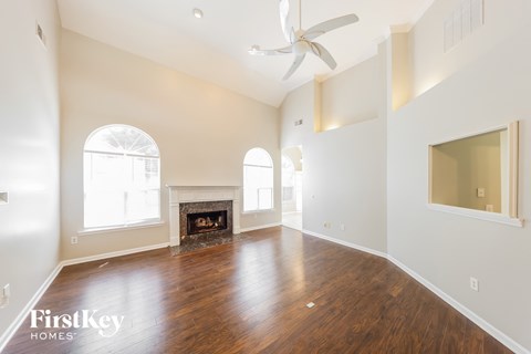 A spacious room with a fireplace and a ceiling fan.