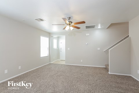 the spacious living room with ceiling fan and carpet