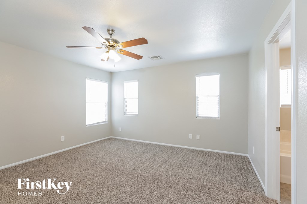 the spacious living room with ceiling fan and carpet