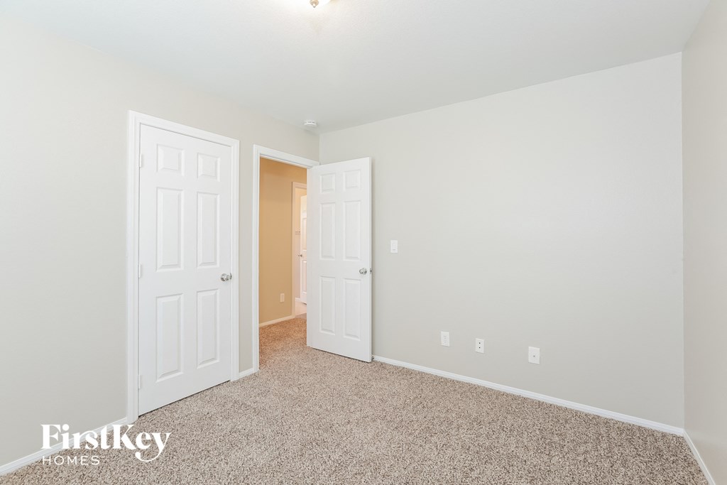 a bedroom with two doors and a carpeted floor