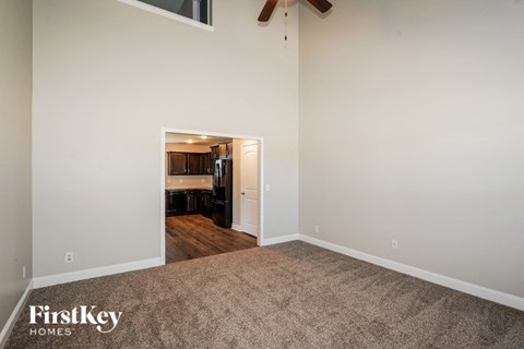 a living room with carpet and a doorway to a kitchen