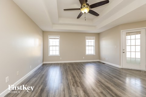 A spacious room with a ceiling fan and wooden flooring.