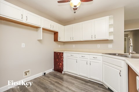 A kitchen with white cabinets and a wooden floor.
