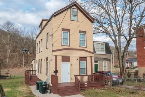 A two-story house with a brown and beige exterior and a white door.