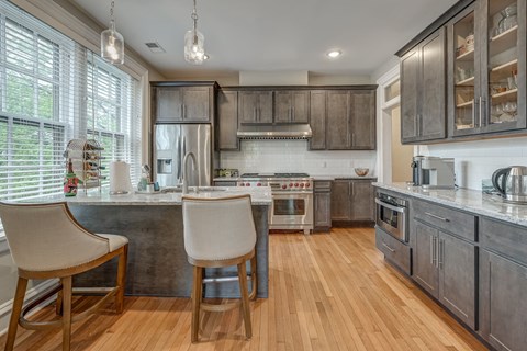 A kitchen with wooden floors and a large island with two chairs.