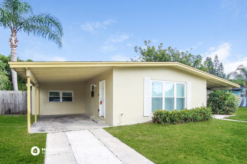 a small yellow house with a lawn and a sidewalk
