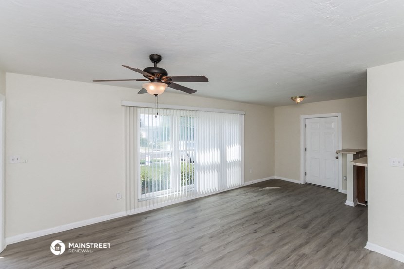 an empty living room with a ceiling fan and a window
