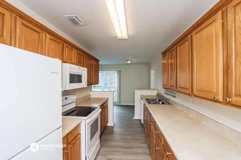 an empty kitchen with wood cabinets and white appliances