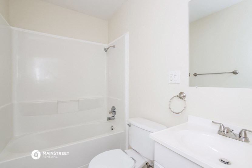 a white bathroom with a tub and a sink and a toilet