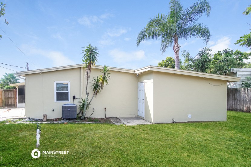 a small white house with palm trees and a lawn