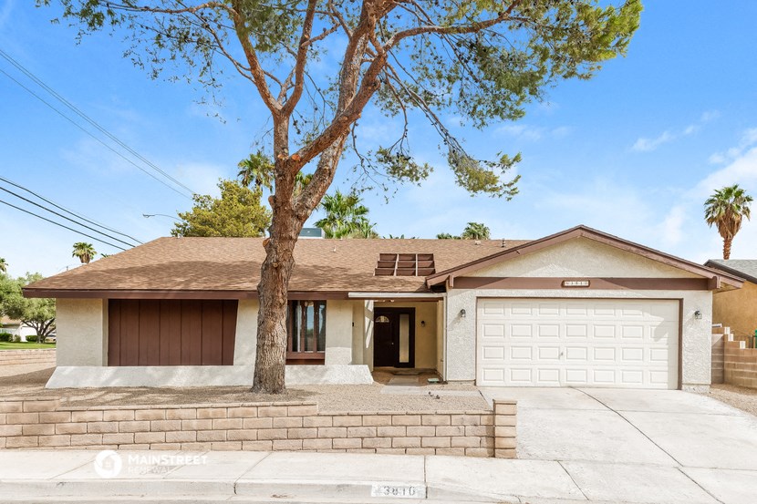 a white house with a garage door and a tree