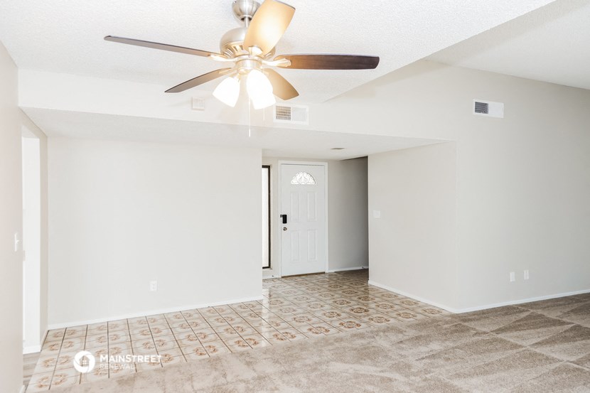 a renovated living room with white walls and a ceiling fan