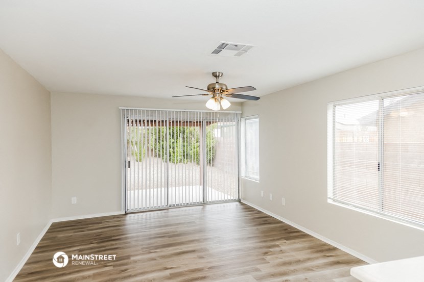 an empty living room with a ceiling fan and a sliding glass door
