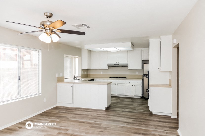 an empty kitchen with white cabinets and a ceiling fan