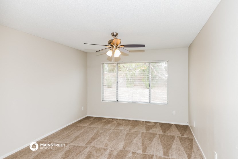 an empty living room with a ceiling fan and a window