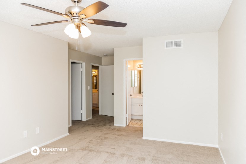 a living room with a ceiling fan and a hallway to a bathroom