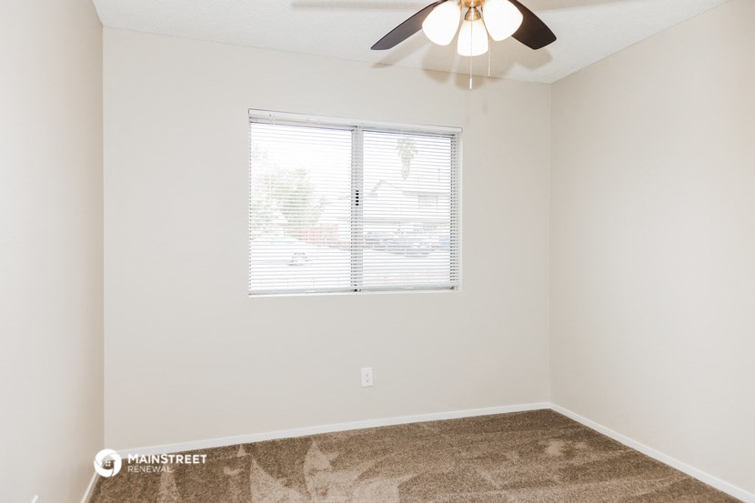 a bedroom with a window and a ceiling fan