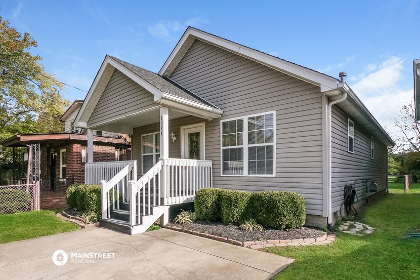 a gray house with a porch and a driveway